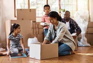 family packing moving boxes sitting on the floor